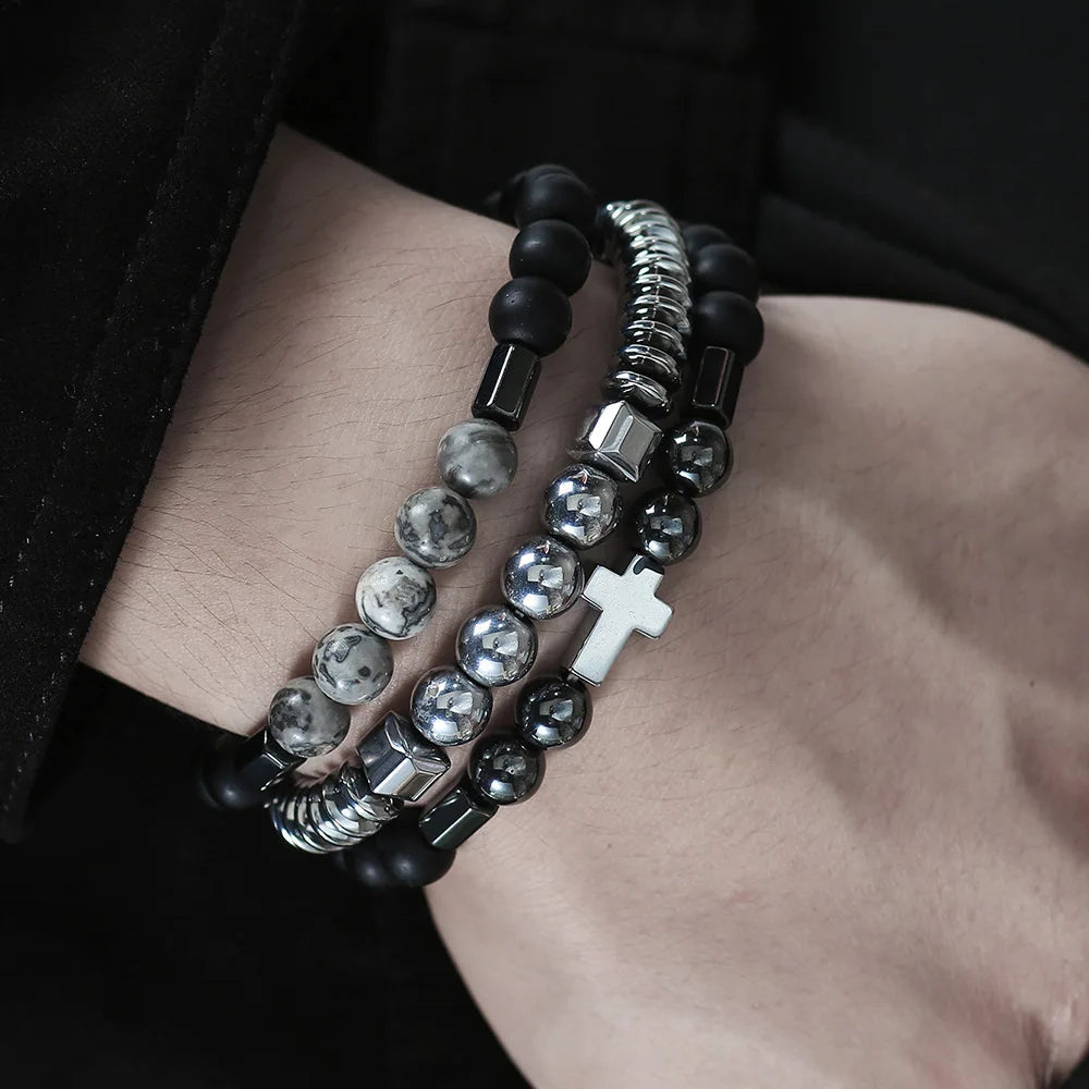 Close-up of a wrist wearing multiple beaded bracelets with a cross charm.