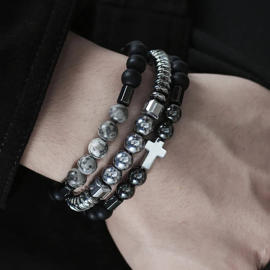 Close-up of a wrist wearing multiple beaded bracelets with a cross charm.